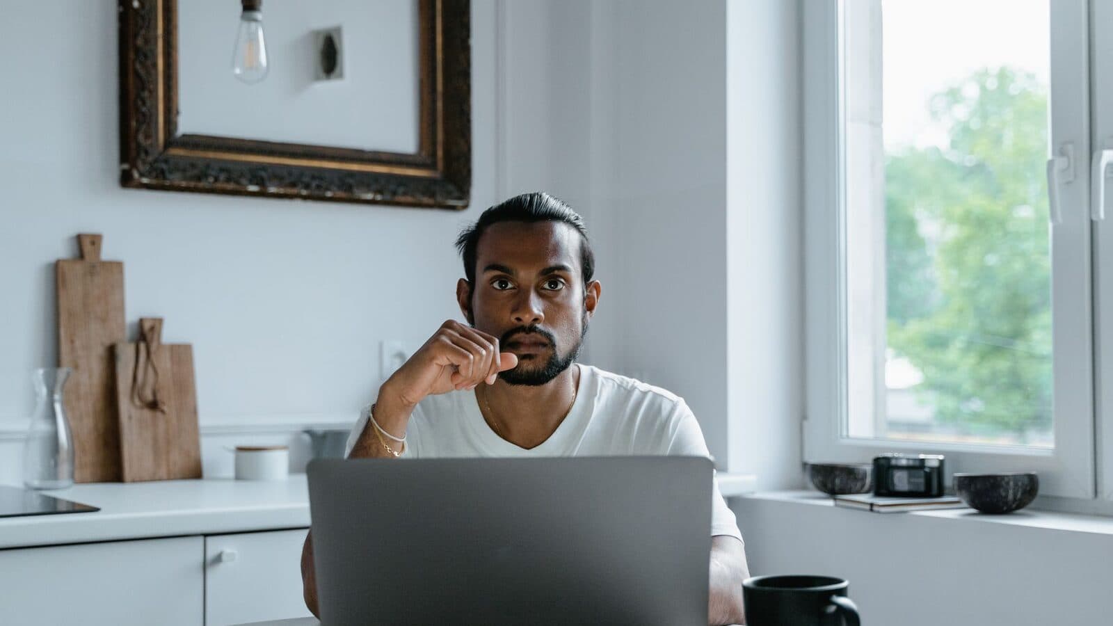 Man werkt geconcentreerd achter een laptop met koffie naast zich